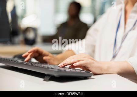 Close up of programmer in Silicon Valley company office developing software using PC, writing code. IT professional typing on computer keyboard, debugging applications to resolve issues Stock Photo