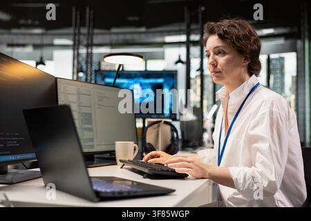 Programmer at office desk using machine learning programming languages displayed on PC screen. Worker using computer in AI company workspace to run deep learning algorithms simulations Stock Photo