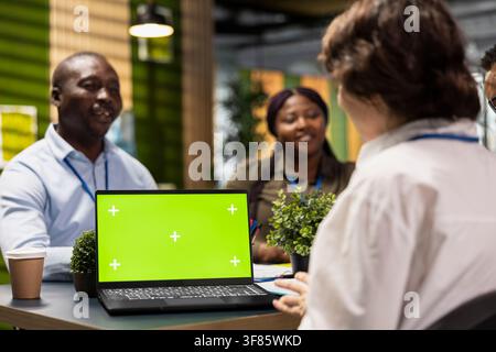 Green screen laptop next to programmers brainstorming ways to develop applications in startup office. Engineers optimizing performance with mockup notebook by debugging application code Stock Photo