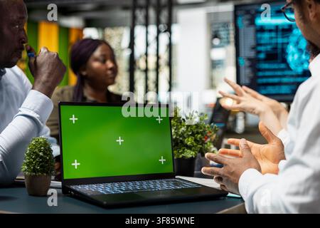 Chroma key laptop next to programmers implementing AI solutions to increase productivity. Close up of isolated screen notebook and workers discussing software development roadmap in startup office Stock Photo