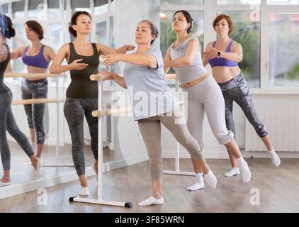 Senior woman practicing arabesque with ballet instructor in amateur class Stock Photo