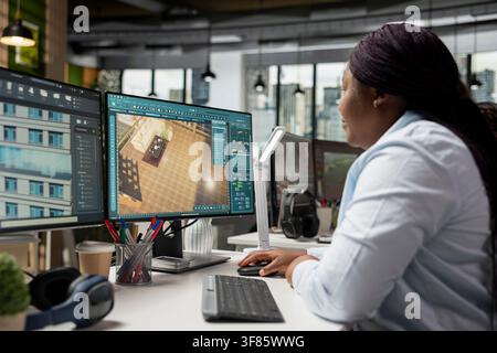Black female graphic designer using CAD software to create a modern floor plan, 3D rendering program on dual monitors. Architectural design with virtual assets used for remodeling layout. Stock Photo