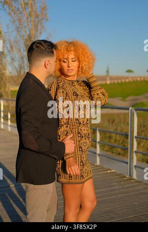 Couple embracing on a boardwalk, enjoying a warm golden hour outdoors Stock Photo