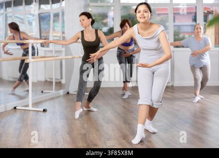 Young female amateur ballet dancer practicing moves at group session Stock Photo
