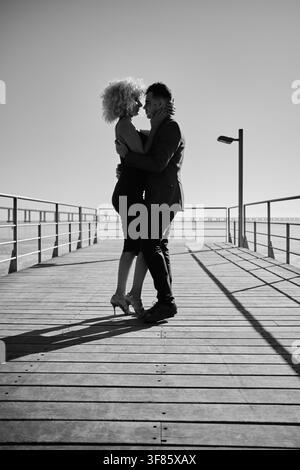 Passionate couple embracing and dancing tango on a sunny boardwalk Stock Photo