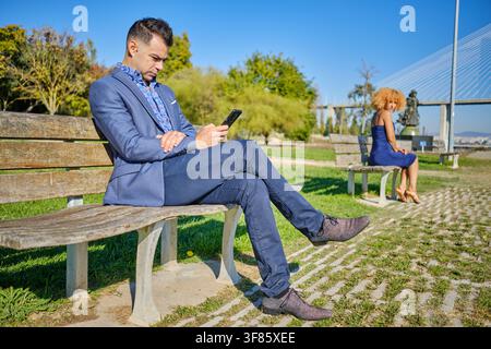 Man focused on phone with an ignored woman looking away at a distance Stock Photo