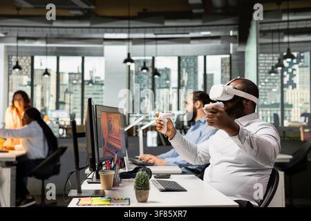 Engineer uses VR glasses to design futuristic video game lobby, creating a fantasy world in cyberspace with software and virtual reality assets. Game developer working in the gaming industry. Stock Photo