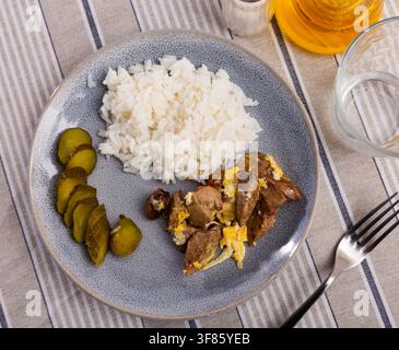 Fried omelette with rabbit liver, boiled rice and pickled cucumber Stock Photo