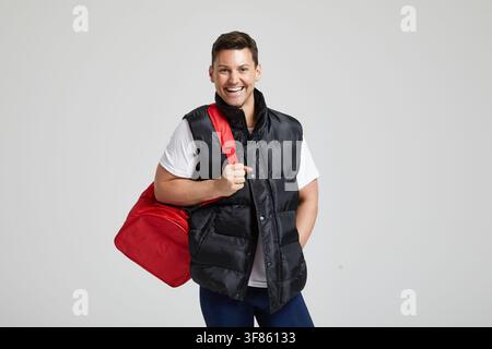 An unnamed man holds the strap of a red duffel bag in a studio setting in London, England, United Kingdom, on 17 March 2017. Stock Photo