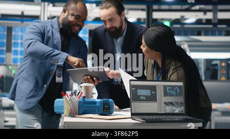 African american technicians examining solar panels in a manufacturing plant, reflecting teamwork and sustainability for solar power infrastructure. Precision for clean energy. Camera B. Stock Photo