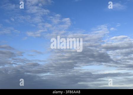 An elongated field of slightly greyish-grey cumulus clouds (Cumulus radiatus, Cu ra), colloquially known as a 'cloud street', in the top right, high Stock Photo