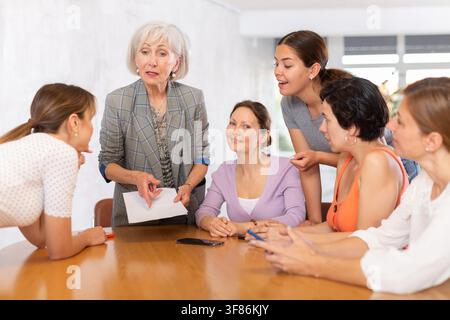 Elderly female tutor communicating with women in speaking club Stock Photo