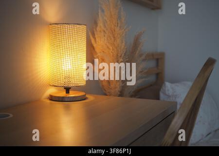 Soft light shines from a lamp on a wooden table in a room Stock Photo