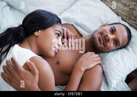Above, couple and relax in bedroom with smile, love and partner support on calm morning. Portrait, people or laying down at house with embrace, spouse Stock Photo