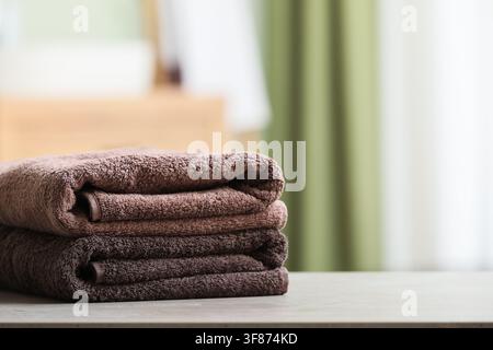 Stack of clean brown and dark brown folded towels on a bathroom counter with blurred background, the soft textile items are neatly piled, hygiene and Stock Photo