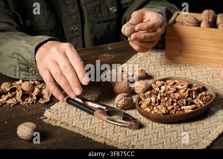 Woman with walnuts and nutcracker on wooden table Stock Photo