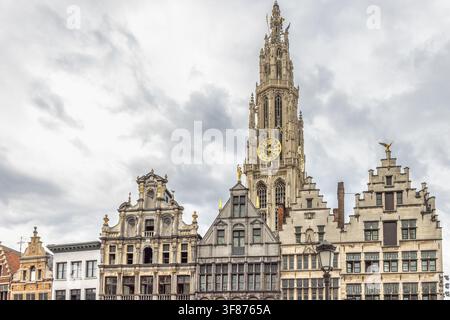 Antwerp town in Belgium, Europe. Dramatic View of Historic European Town Square with Grand Bell Tower and Ornate Gable Houses Under a Cloudy Sky Stock Photo