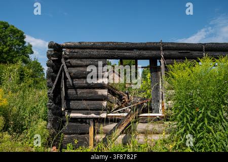 Izborsk, Pskov Oblast - July 26, 2026. A fire-damaged log structure with blackened timber, a missing roof, and a large window opening exposing collaps Stock Photo