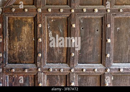 Close-up texture of a historic paneled wooden gate with iron studs and ring handle at Lanhydrock estate in Cornwall, photographed on 28.08.2024. Stock Photo