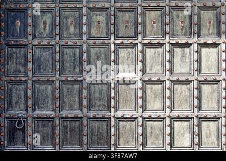 Close-up texture of a historic paneled wooden gate with iron studs and ring handle at Lanhydrock estate in Cornwall, photographed on 28.08.2024. Stock Photo