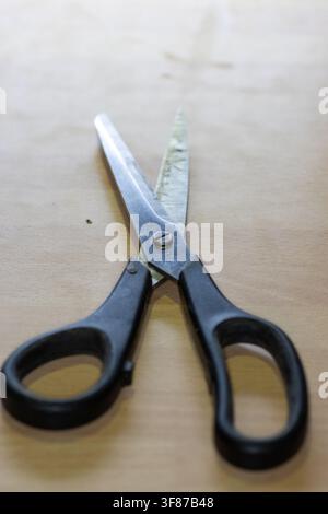 light duty black handle paper scissors on a fake wood kitchen surface super close-up with shallow depth of field Stock Photo