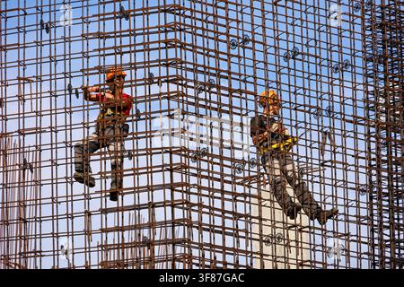 Two workers installers on construction site. Housing construction, builders working on scaffolding Stock Photo