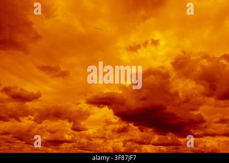 Dramatic orange and golden clouds fill the sky at sunset, creating an intense fiery atmospheric cloudscape Stock Photo