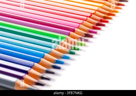 Row of sharp colored pencils arranged in a vibrant rainbow spectrum on a pure white background. Close-up diagonal view representing creativity, art, b Stock Photo