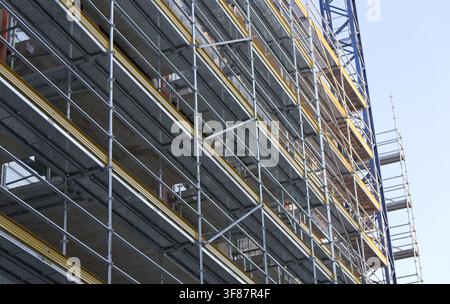 Metal scaffolding covering a building under construction, providing access for workers to complete the new architecture and development project. Bulga Stock Photo