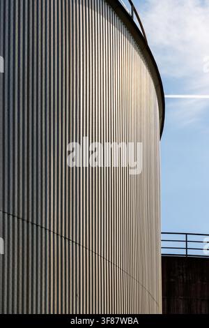 Curved corrugated metal silo wall with vertical lines and sunlight Stock Photo