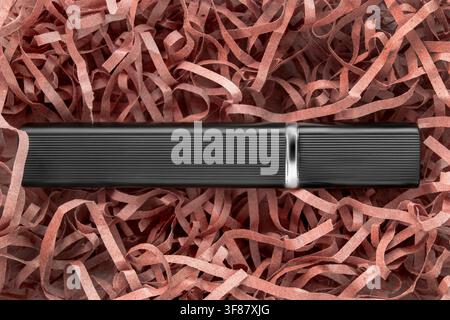 Black elegant perfume atomizer lying in brown shredded packaging paper Stock Photo