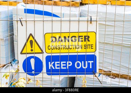 "Danger construction site, keep out" warning sign on a fence outside a compound in a development project Stock Photo