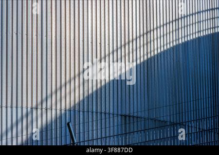 Geometric shadow on ribbed industrial silo wall. Repetitive vertical lines and sweeping diagonal shadow create an abstract minimalist pattern Stock Photo