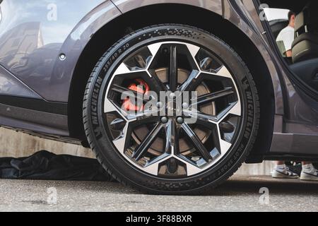Lindau, Switzerland, August 9, 2026. Close up of alloy wheel rim with red brake caliper and Michelin tire mounted on dark grey Zeekr electric passenge Stock Photo