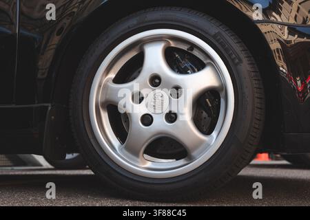 Lindau, Switzerland, August 9, 2026. Detailed close up shot of five spoke silver Cup alloy wheel with Porsche crest center cap and Pirelli tire on bla Stock Photo