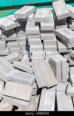 Stacked concrete pavers stacked and piled, in construction site or storage area, with concrete pavers, wooden pallets, from a top-down perspective Stock Photo