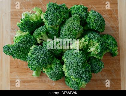 Broccoli arranged on a cutting board, in wooden surface, with broccoli, cutting board, from a top-down view perspective, with green, brown accents Stock Photo