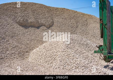 Gravel pile stationary, in construction site, with gravel, green machinery, from a side view perspective, with beige, green accents, and industrial Stock Photo