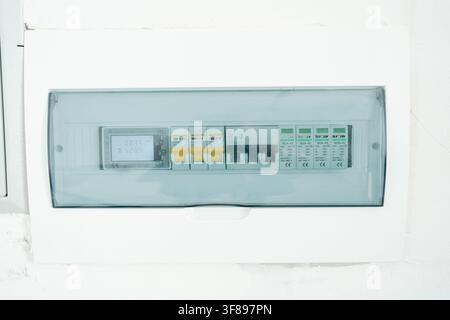 A top-down view of an installed and operational electrical panel mounted on a wall, featuring circuit breakers and a neutral functional design, home Stock Photo