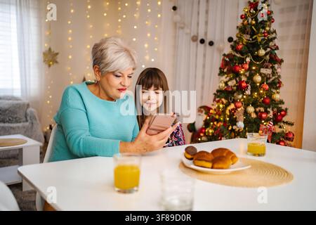 Grandmother and granddaughter using smartphone at Christmas holiday Stock Photo