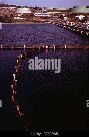 The boom system at the North East Petroleum Tanker Terminal in Tiverton, the largest tanker terminal in the Northeast, which encloses each ship with a boom to contain oil spills, photographed in 1973 as part of the DOCUMERICA program by the Environmental Protection Agency. Stock Photo