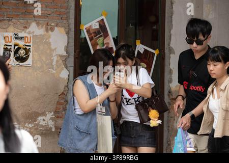 BANGKOK, THAILAND - AUG 8, 2026: Female tourists reviewing photos on a smartphone, front view, Song Wat Road Stock Photo