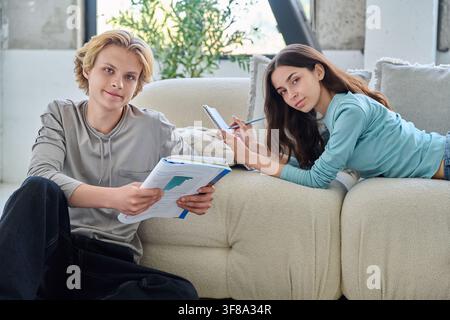 Two smiling young students studying together with books at modern home. Stock Photo
