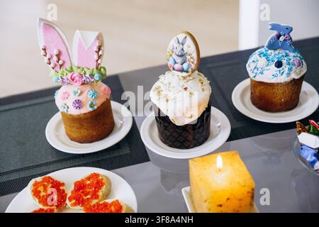Easter festive table setting with traditional food, cupcakes and red wine at home. Stock Photo