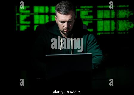Hacker types code on laptop keyboard. Hacker analyzes system vulnerability at night. Hacker monitors server and database access. Hacker launches cyber Stock Photo