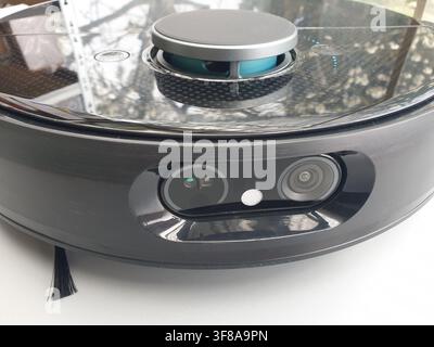 A black robotic vacuum cleaner with advanced sensors is shown closeup Stock Photo