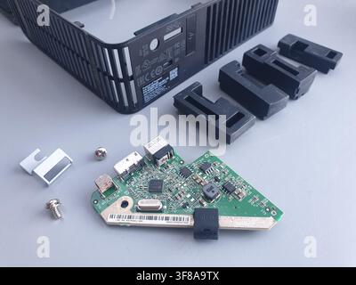 A disassembled computer circuit board and various parts lay on a gray surface Stock Photo