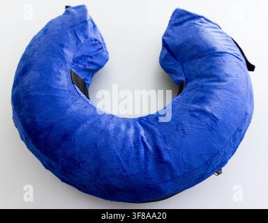 A fluffy blue Ushaped neck pillow rests on a white background Stock Photo