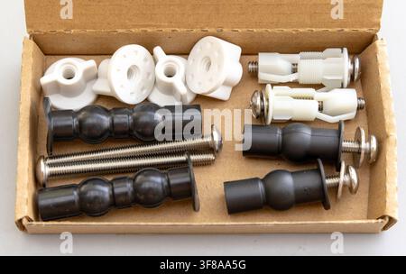 A toilet seat fixing kit with various parts lies in a box Stock Photo