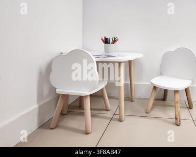 Minimalist children's furniture set featuring two iconic white cloud-shaped chairs and a small table. Providing a dedicated space for creative activit Stock Photo
